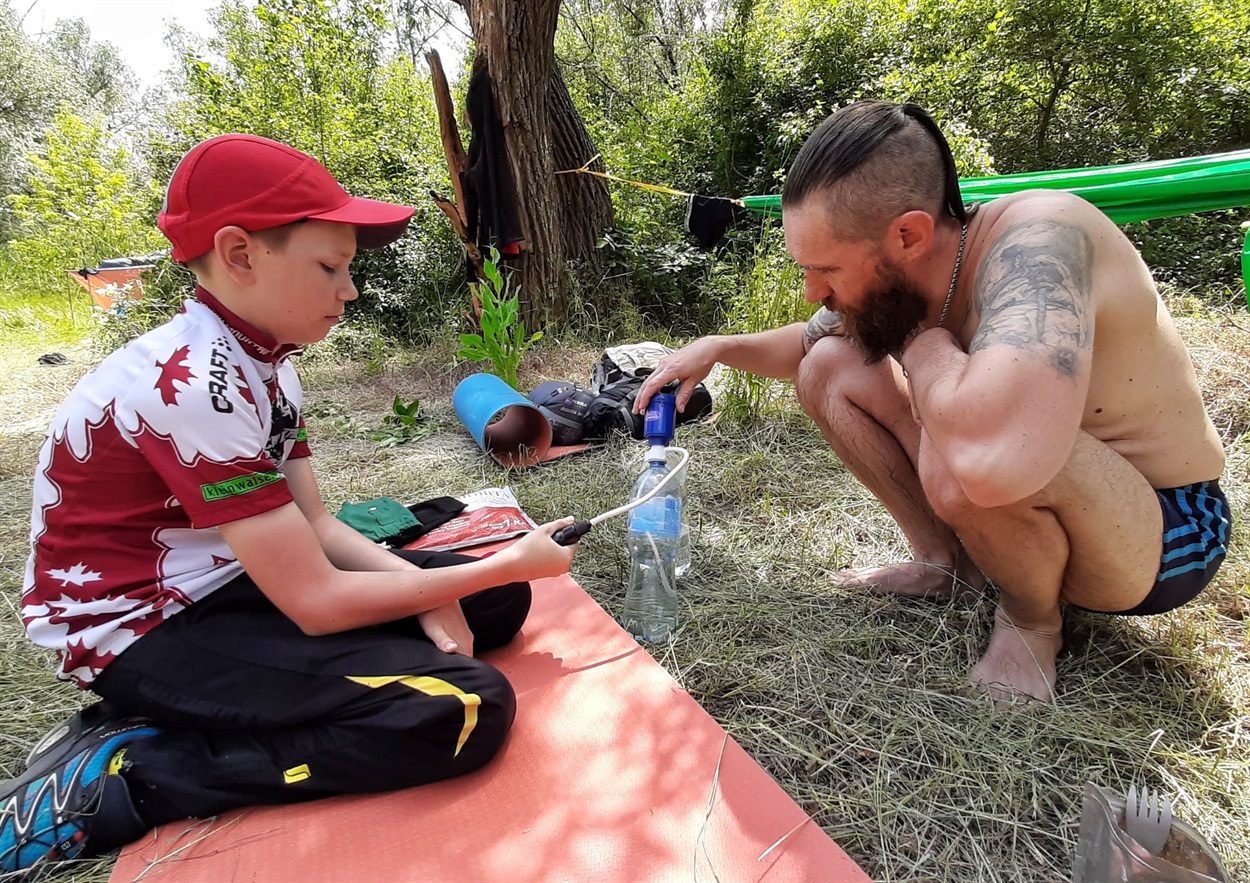Сергій із сином очищує воду в польових умовах.