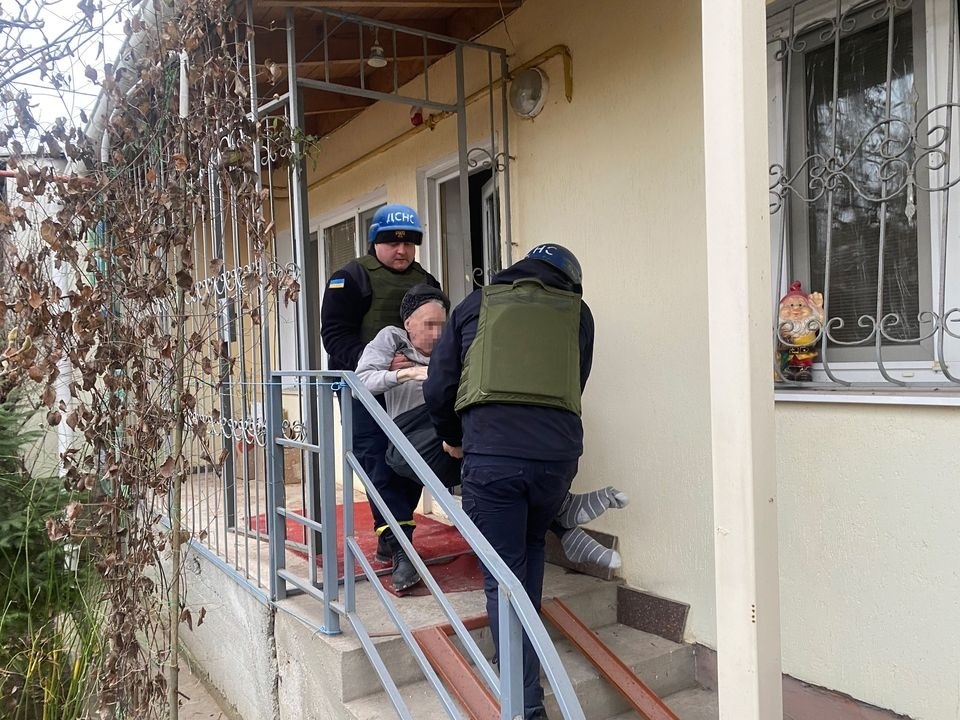 Рятувальники виносять з потрощеного обстрілами будинку постраждалого 